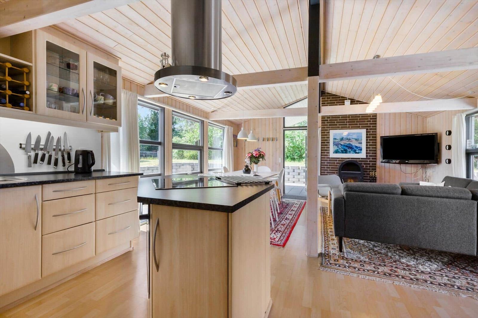Kitchen with island and dining area, living room with sofa and fireplace.