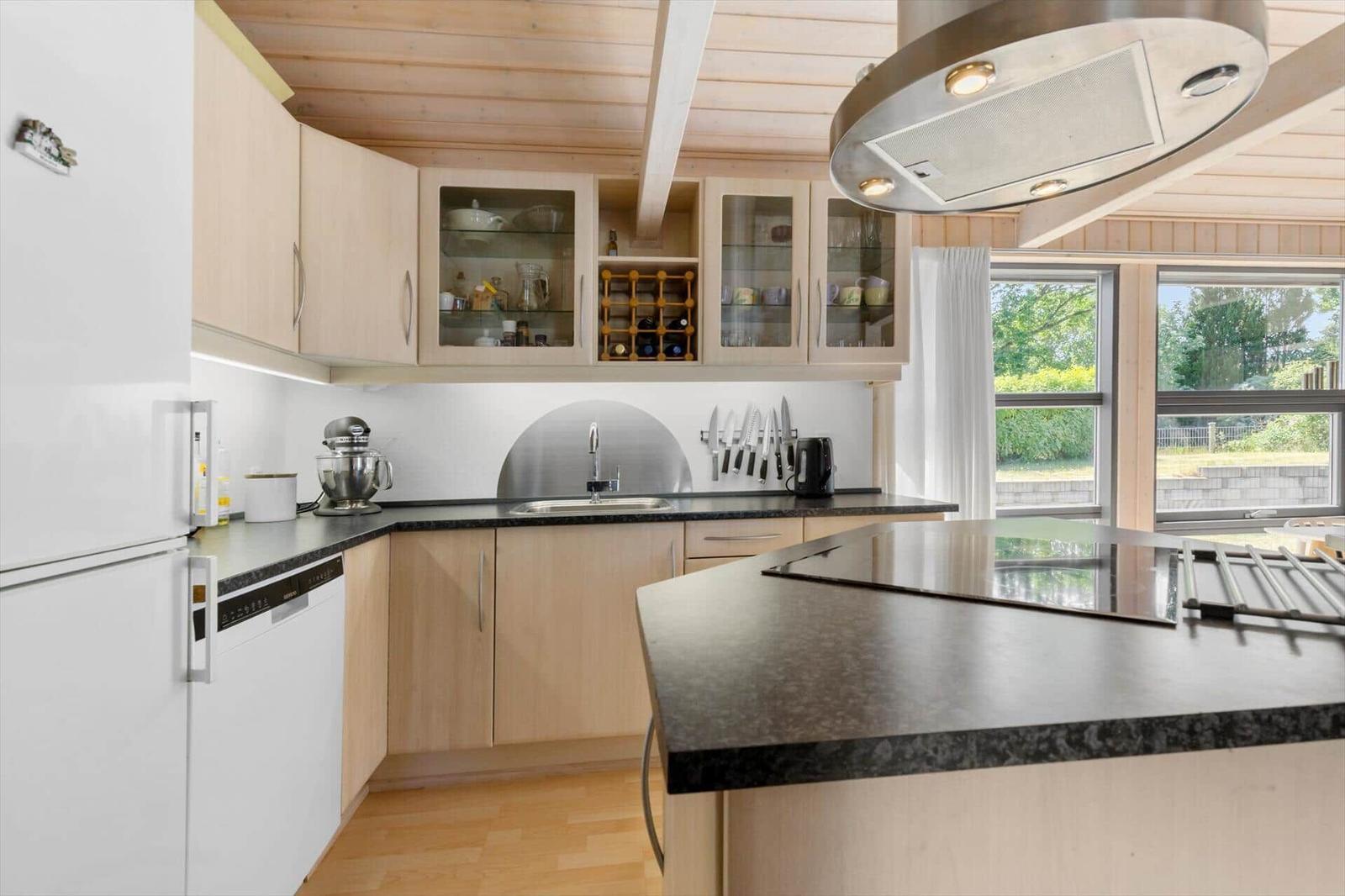 Kitchen with wooden cabinets, stainless steel sink, and island with stove.