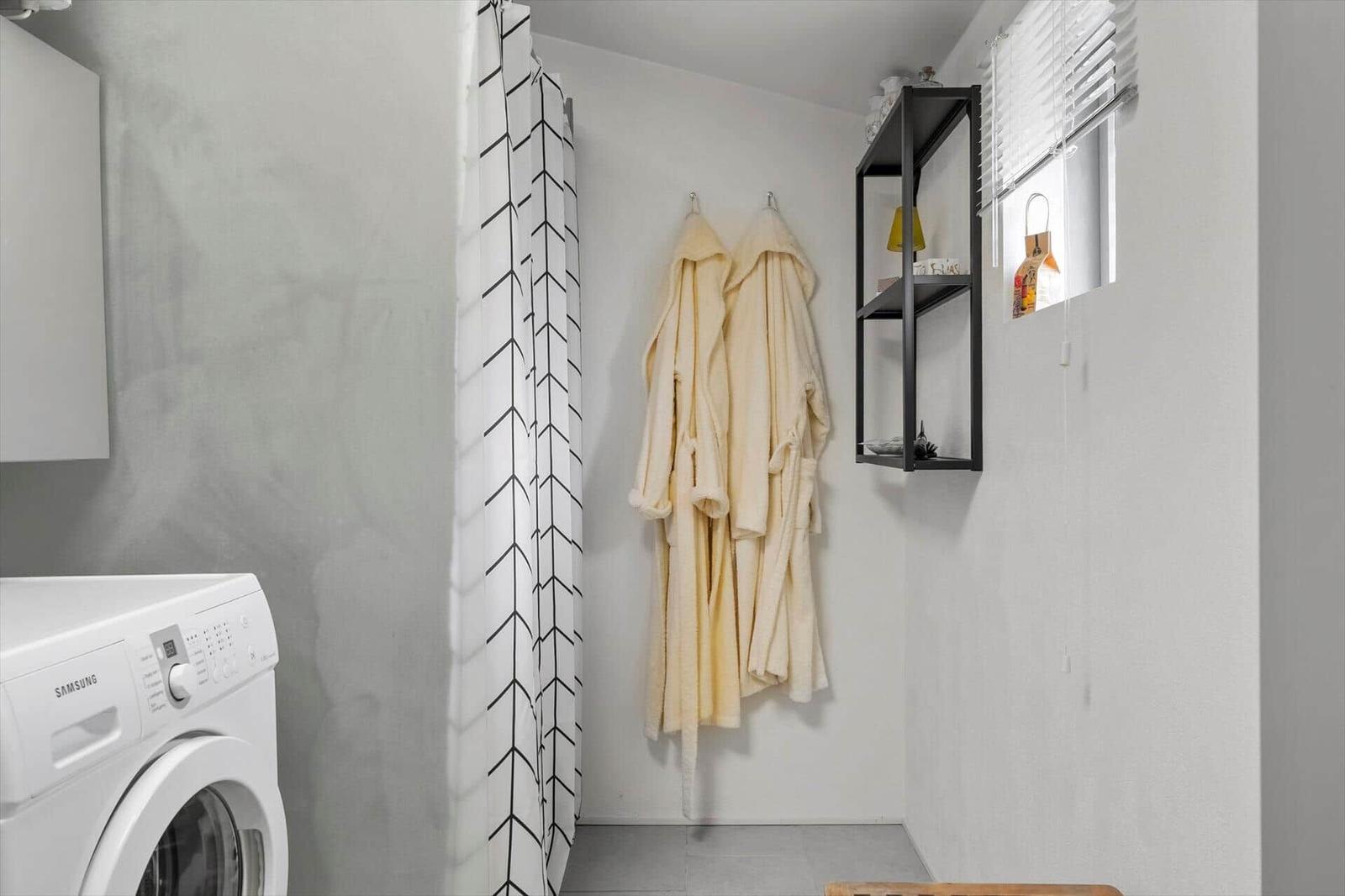 Waschmaschine, Duschvorhang und Bademäntel an der Wand