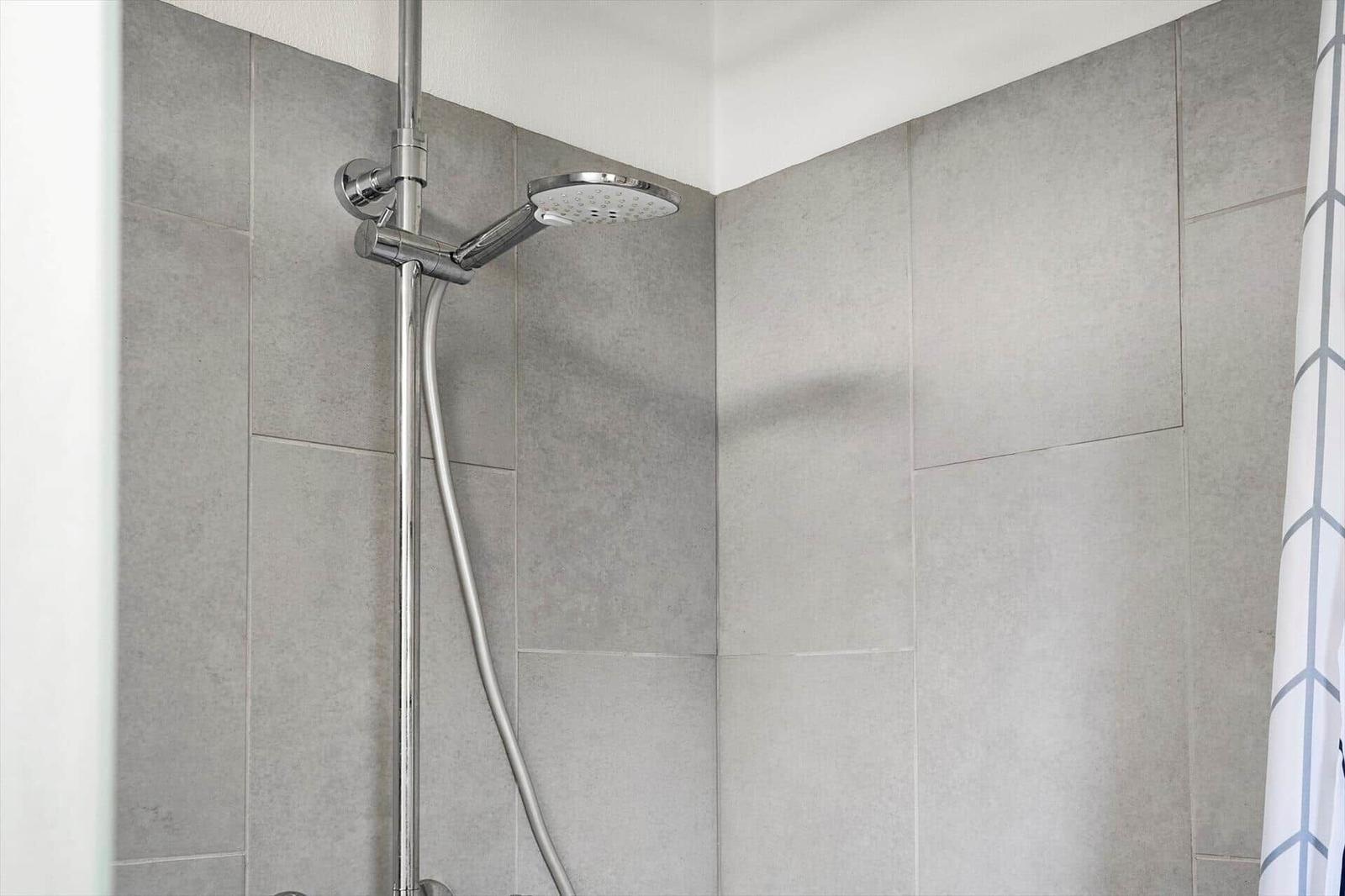Dusche mit Duschbrause und grauen Fliesen