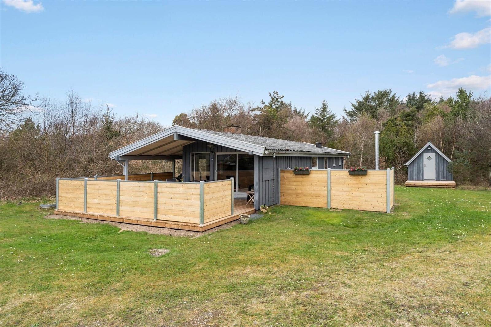 Moderne Holzhütte mit Terrasse und Garten. Nebenhaus mit Schiebetür.