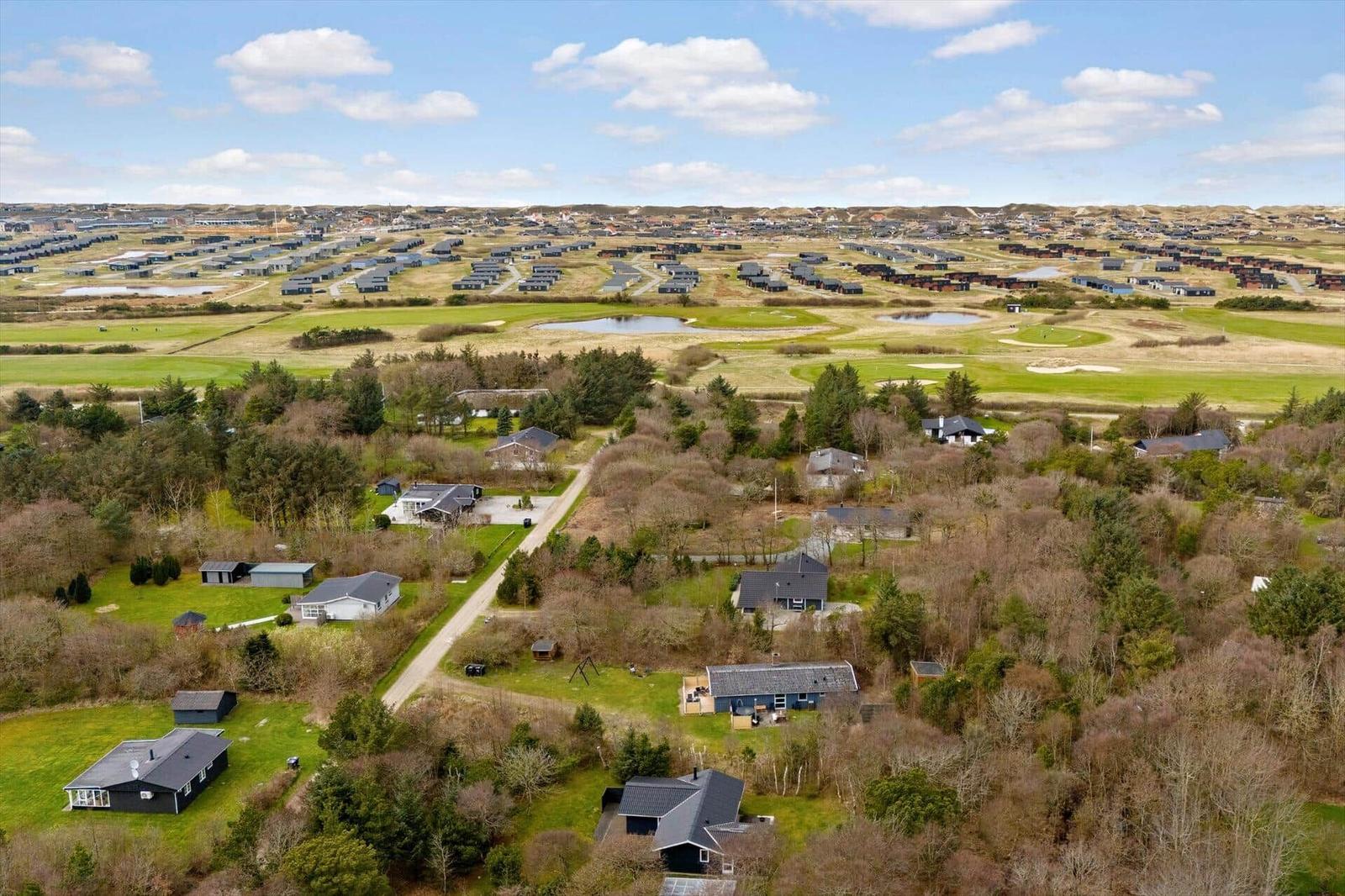 Luftbild von Ferienhäusern und einem Golfplatz in einer grünen Landschaft.