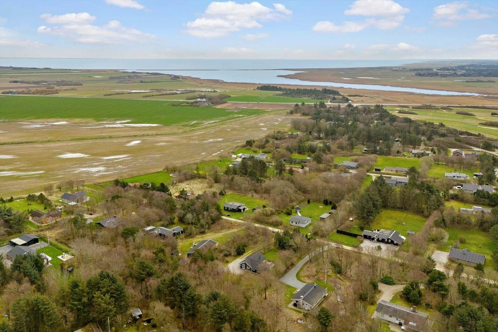 Aerial view of rural area with houses, green fields, and coastal waters.
