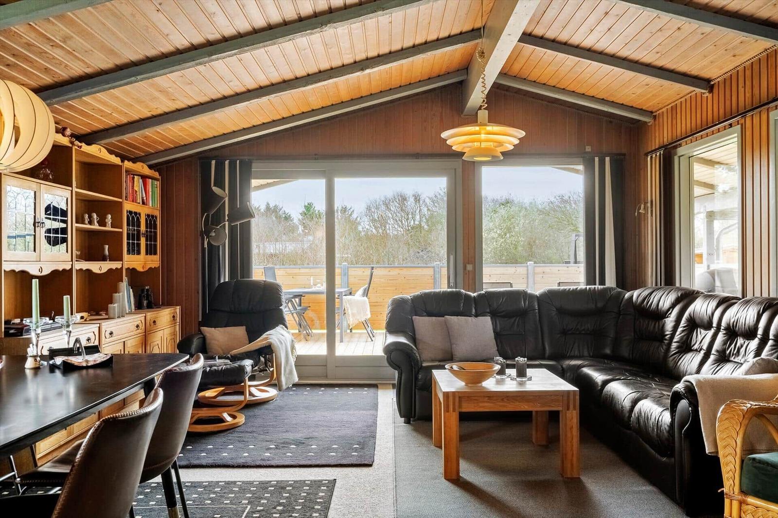 Wohnbereich mit Sofa, Esstisch und Blick auf Balkon