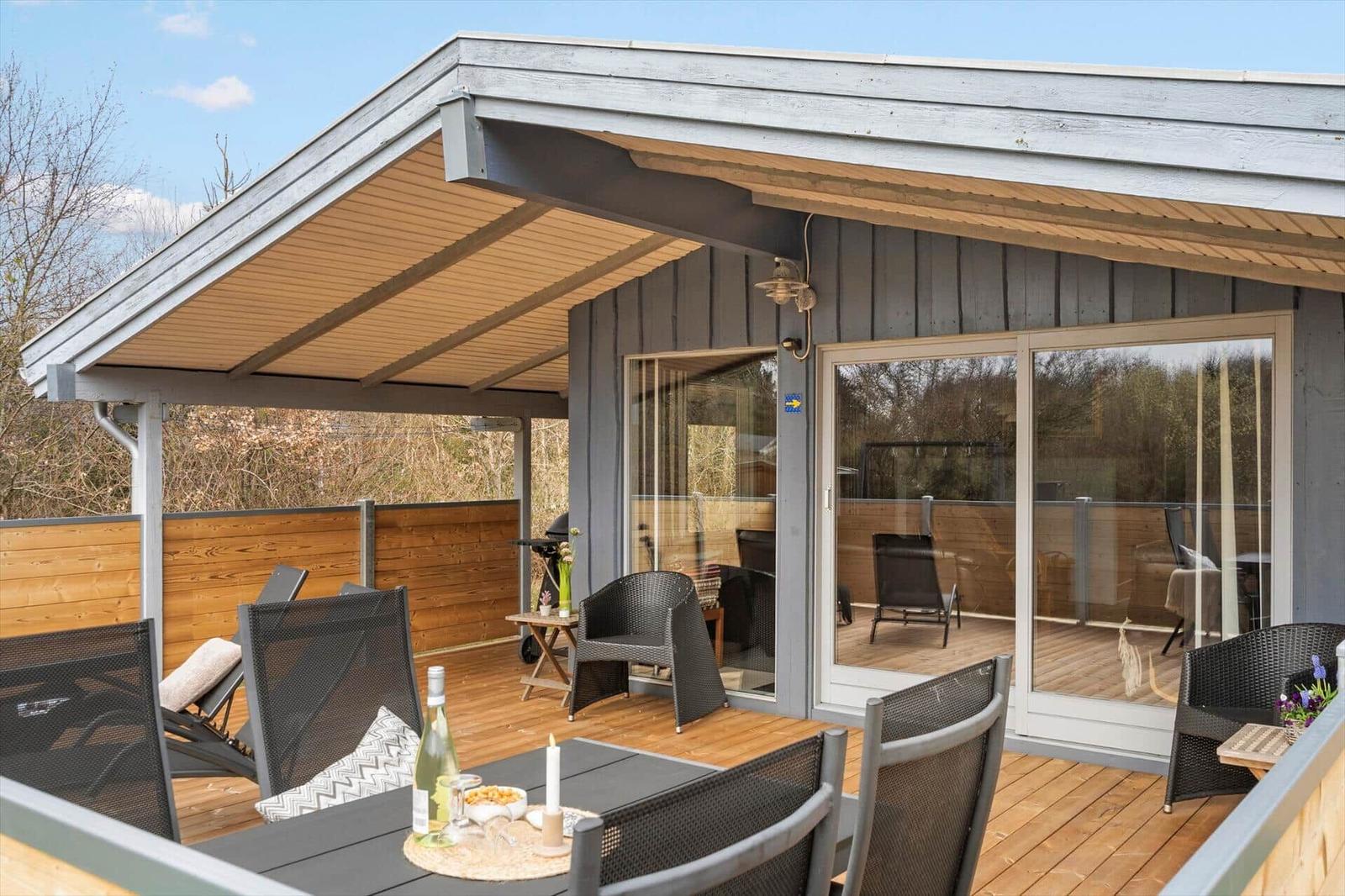 Terrasse mit Sitzgelegenheiten und Grill unter Dach