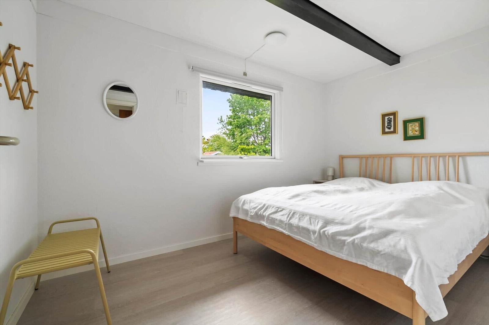 Bedroom with bed, window, and yellow bench.
