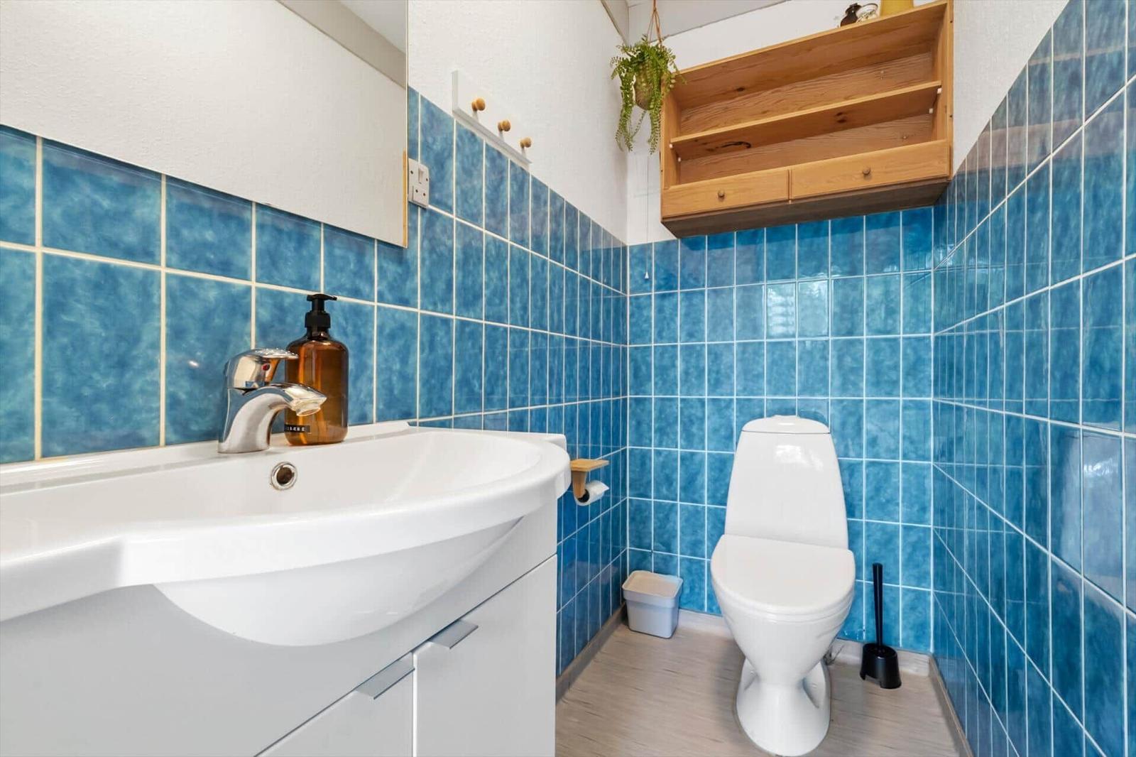 Bathroom with blue tiles, sink, and toilet.