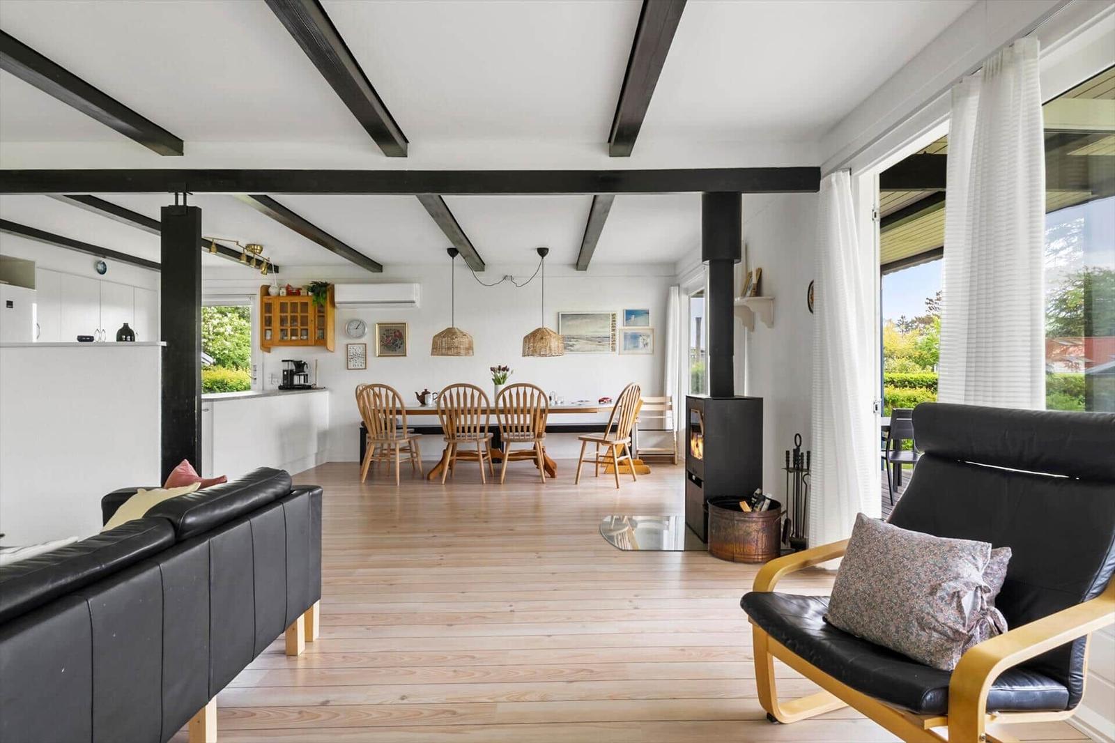 Living area with dining space, wooden floor, and black beams on ceiling.
