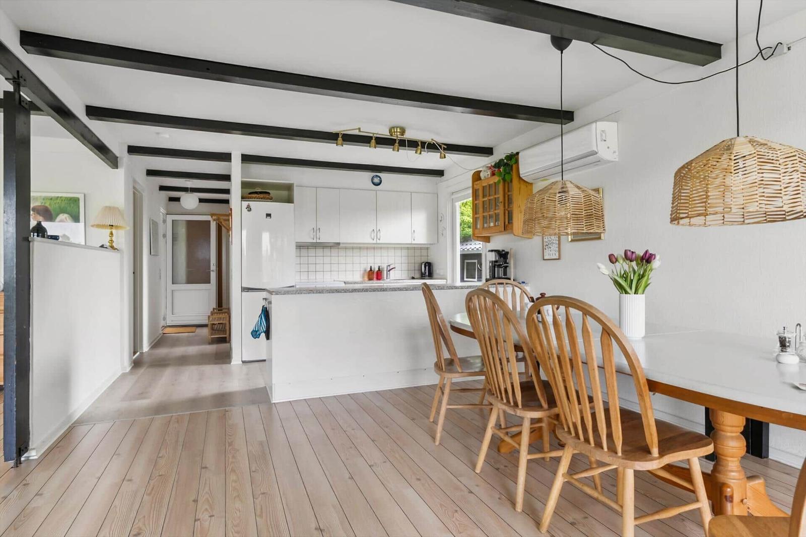Kitchen and dining area with wooden floor, white cabinets, and dining table with chairs.