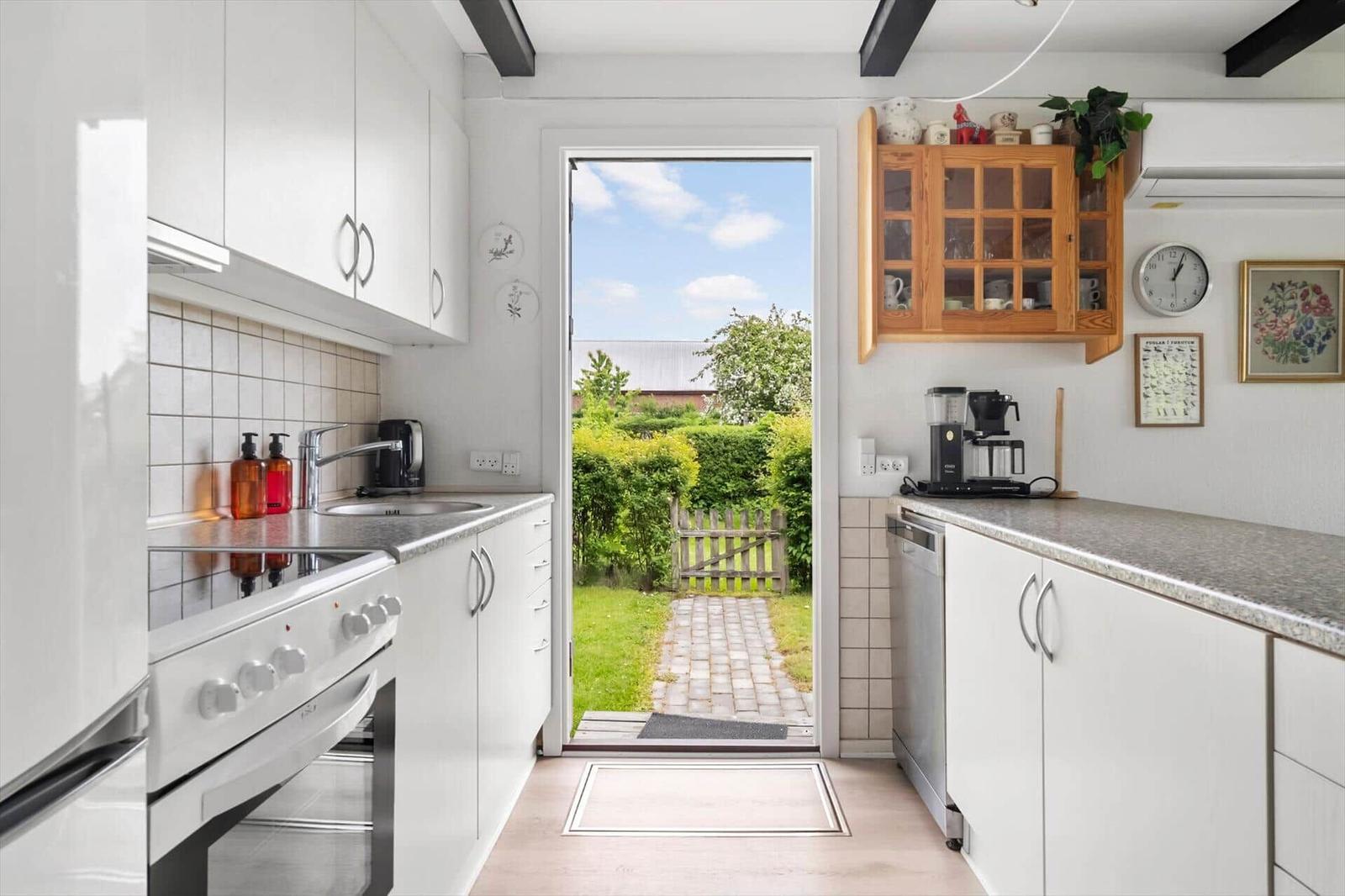 Kitchen with garden view. White cabinets, stainless steel appliances, and wooden cabinets.