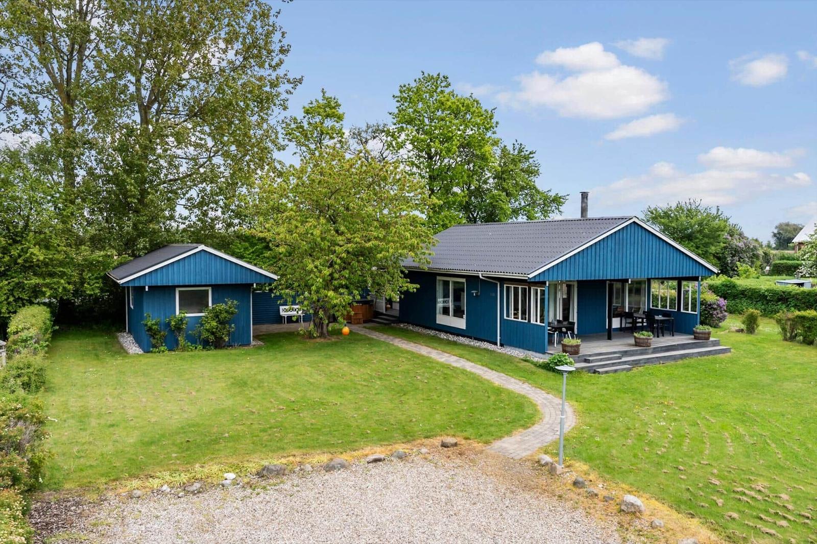 Two blue houses with terrace and garden under blue sky.
