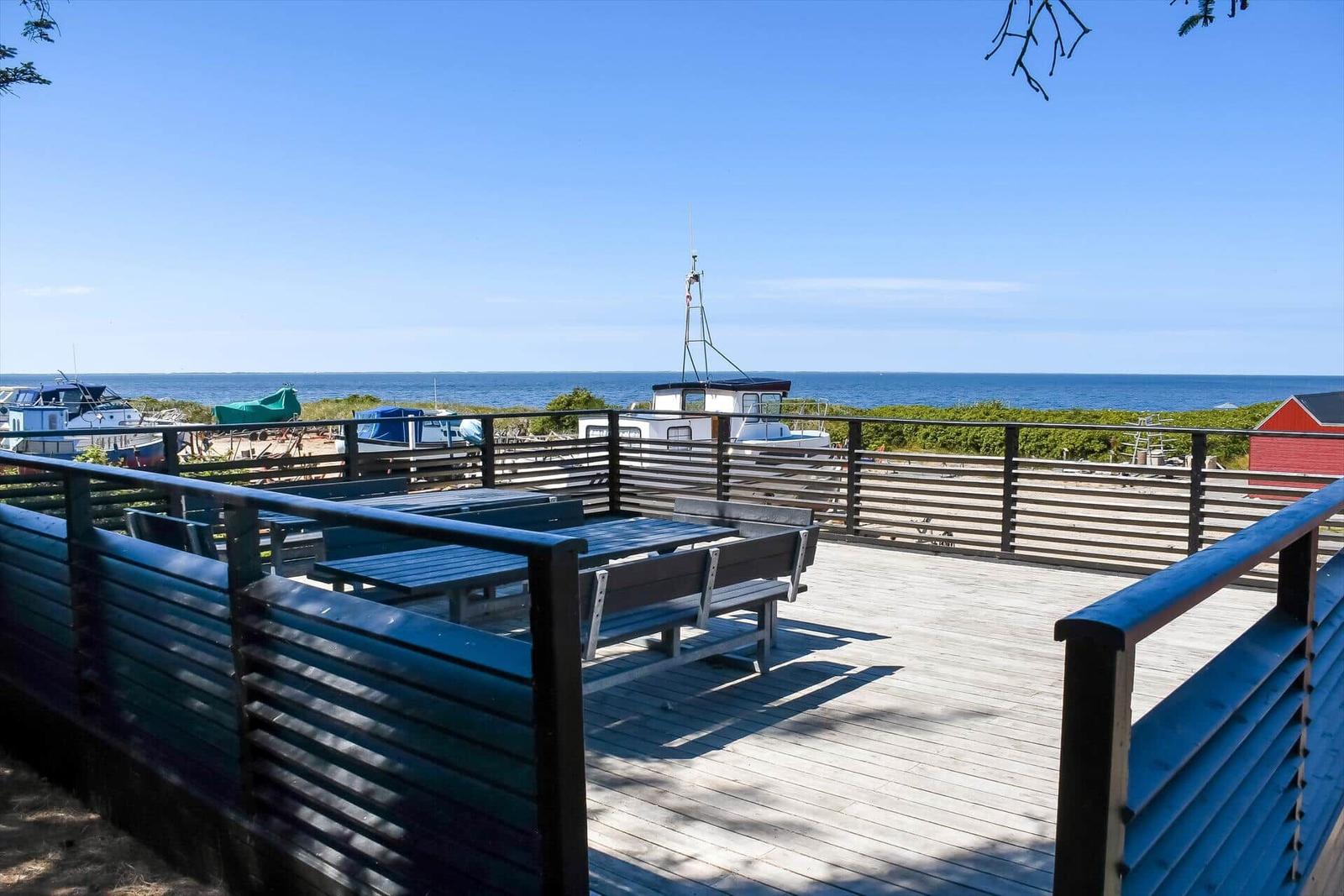 Deck with tables and benches offers view of sea and boats.
