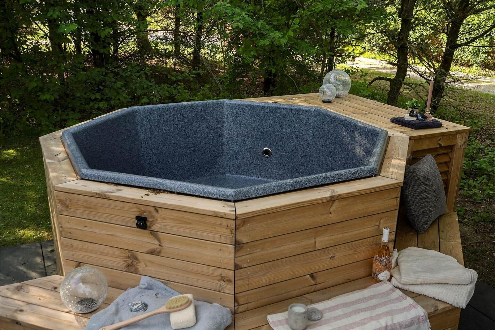 Außenwhirlpool mit Holzrahmen und Umgebung aus Bäumen.