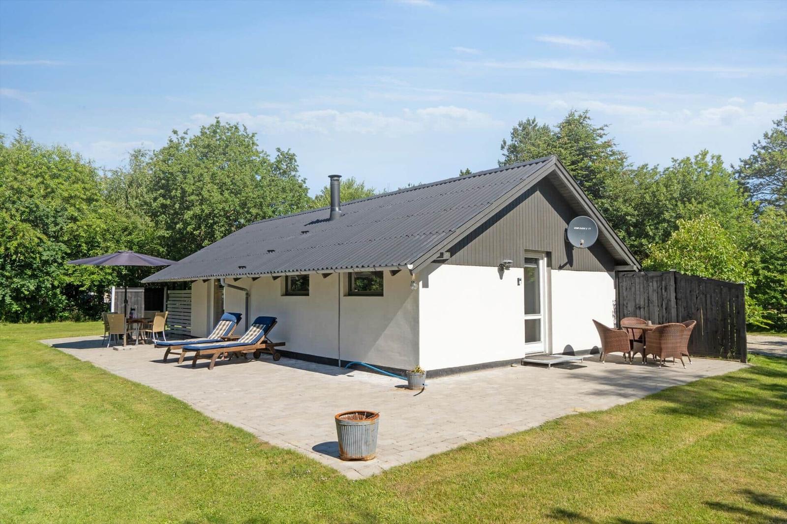 Moderne Ferienhaus mit Terrasse, Liegestühlen und Garten.