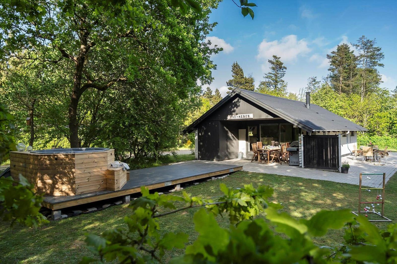 Holzhaus mit Whirlpool, Terrasse und Grillplatz im Grünen.