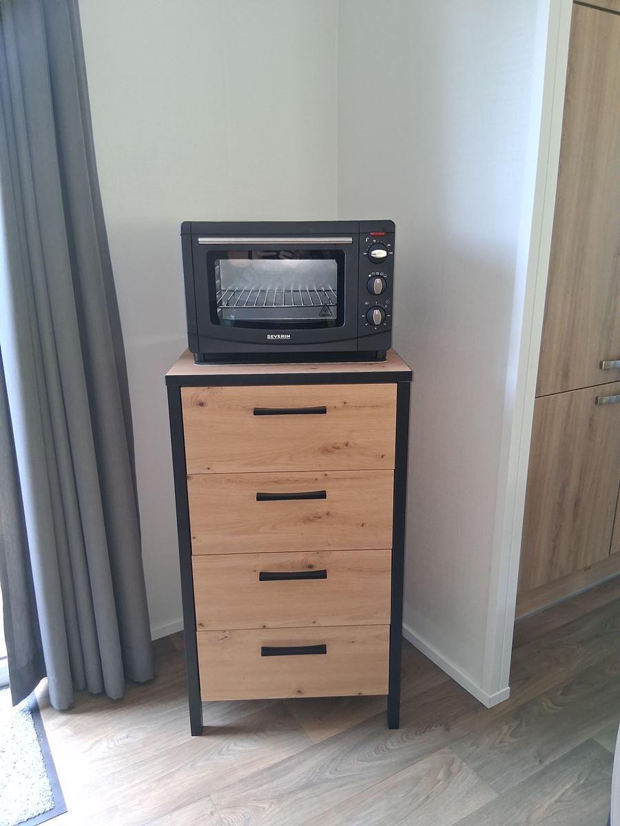 Schwarzer Toaster auf einem Holzschrank mit vier Schubladen.