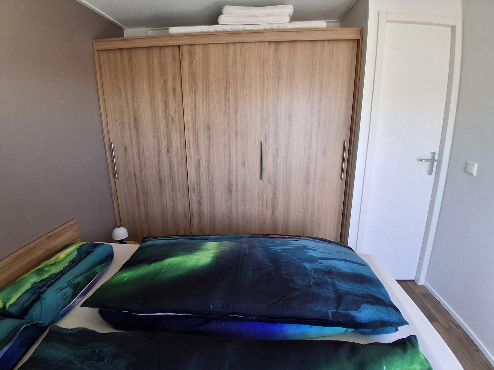 Schlafzimmer mit Bett, Kleiderschrank und Tür