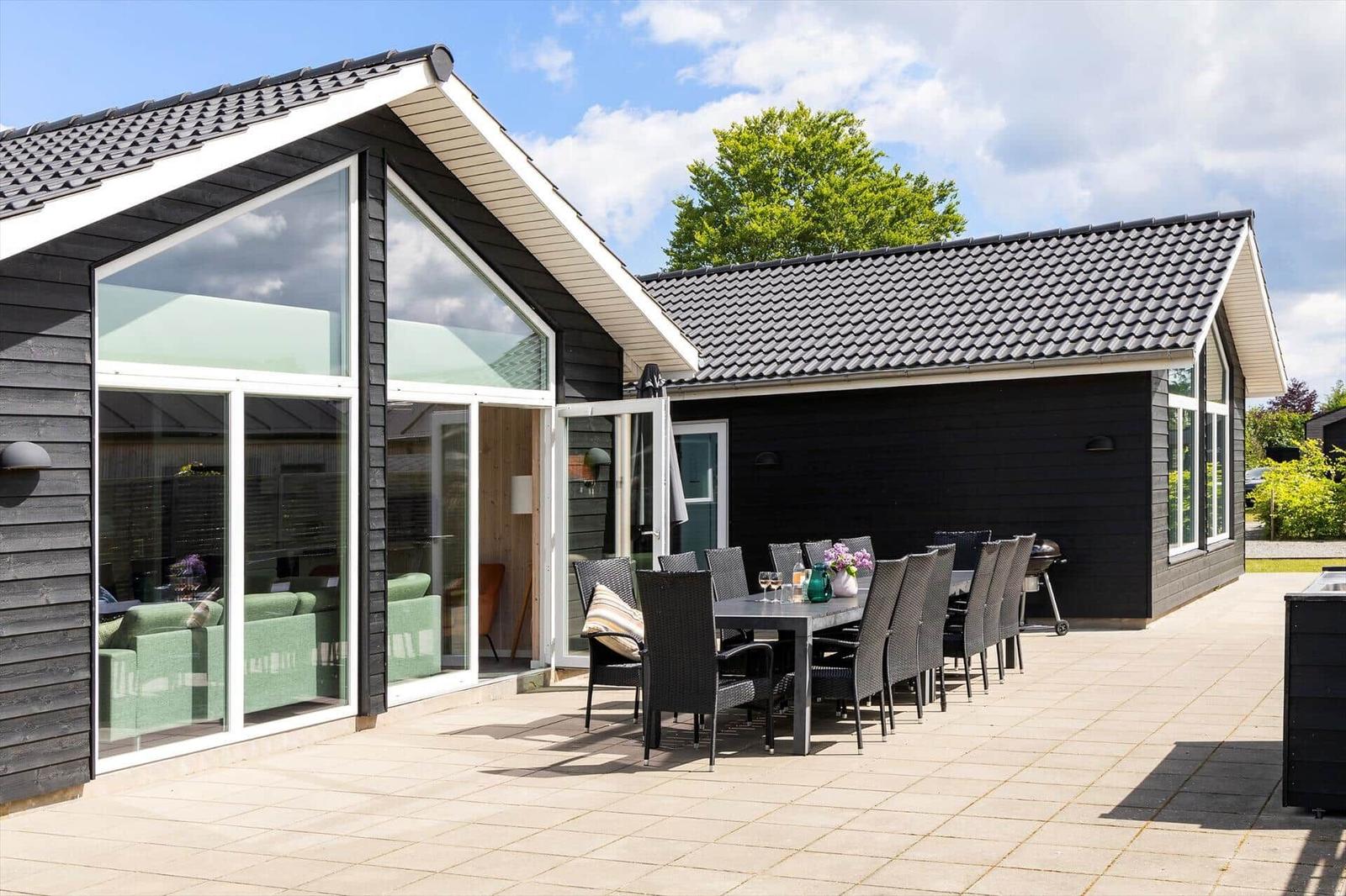 Moderne Villa mit großem Terrassenbereich, Sitzgruppe und Grillplatz.