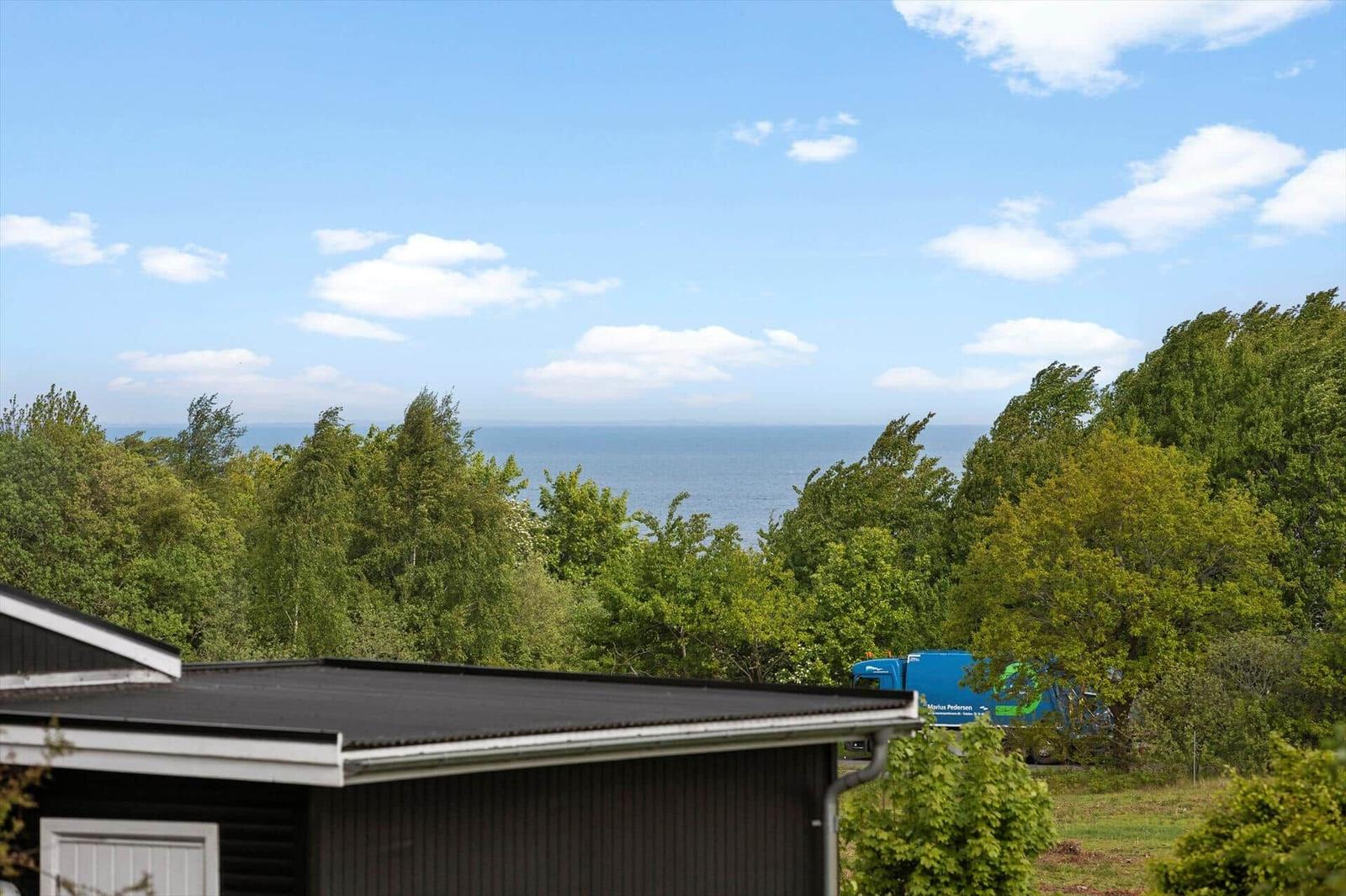 Von der Terrasse bietet sich ein Blick auf das Meer hinter Bäumen.