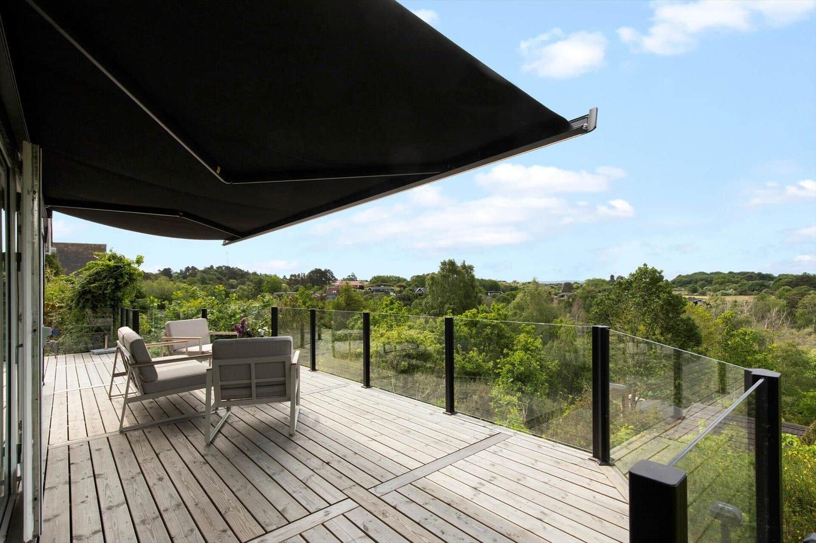 Terrasse mit Sitzgelegenheiten und Blick auf grüne Landschaft.