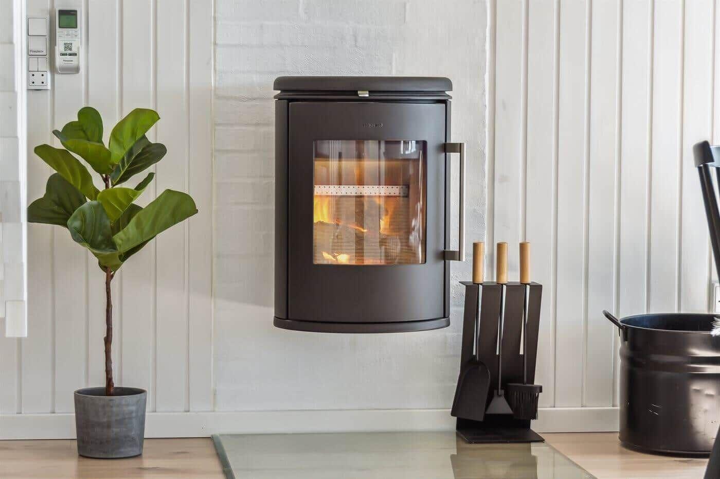 Wandmontierte Feuerstelle mit brennendem Holz, daneben Pflanze und Feuerzeughalter.