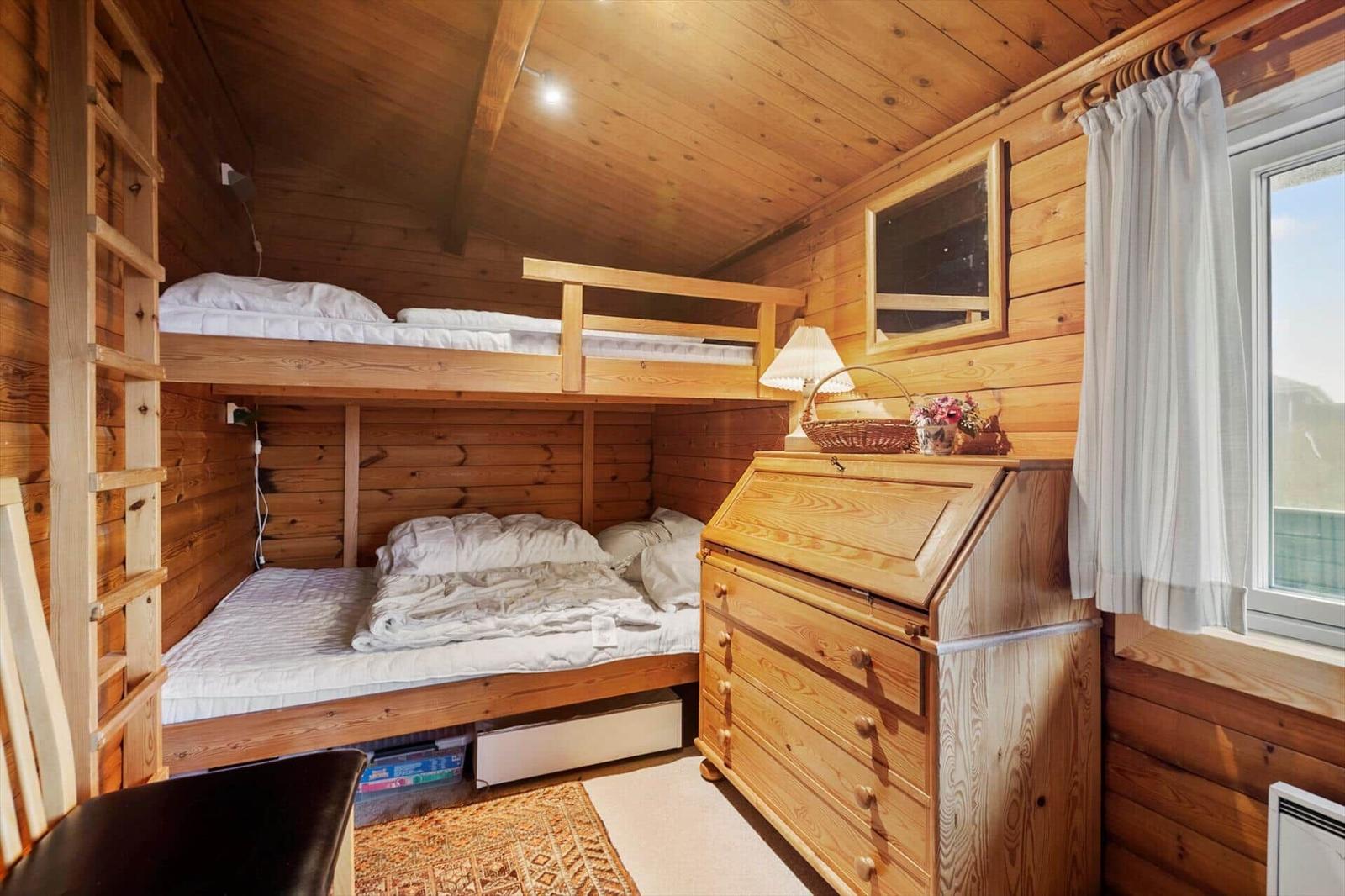 Holzwand mit Spiegel, Schrank und Dekorationen. Fenster und Heizung sichtbar.