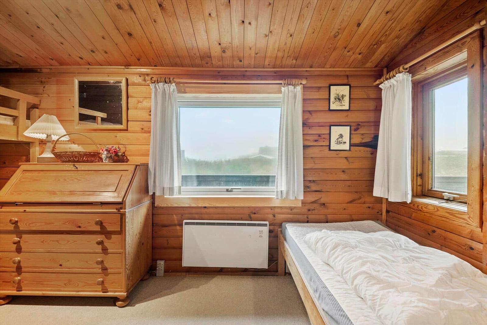 Schlafzimmer mit Holzwand, Bett und Fenster. Decke mit Lampe und Bücherregal.