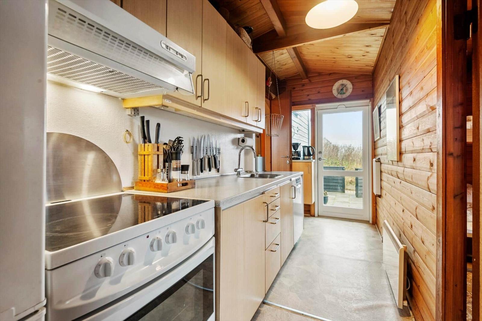 Küche mit Holzwand, Spüle, Kühlschrank und Dunstabzug.
