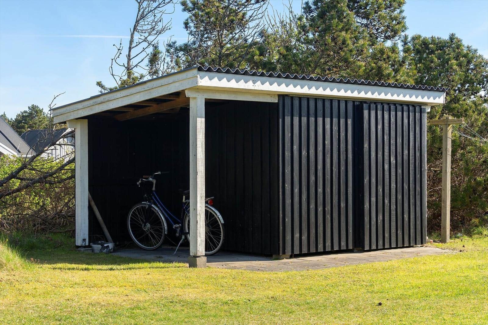 Ein Schuppen mit einem Fahrrad darin und einem Dach aus Wellblech.