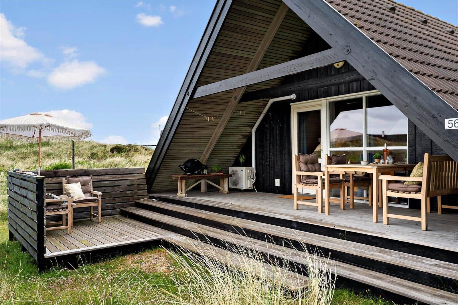 Holzterrasse mit Sitzgelegenheiten und Grill unter einem Dach