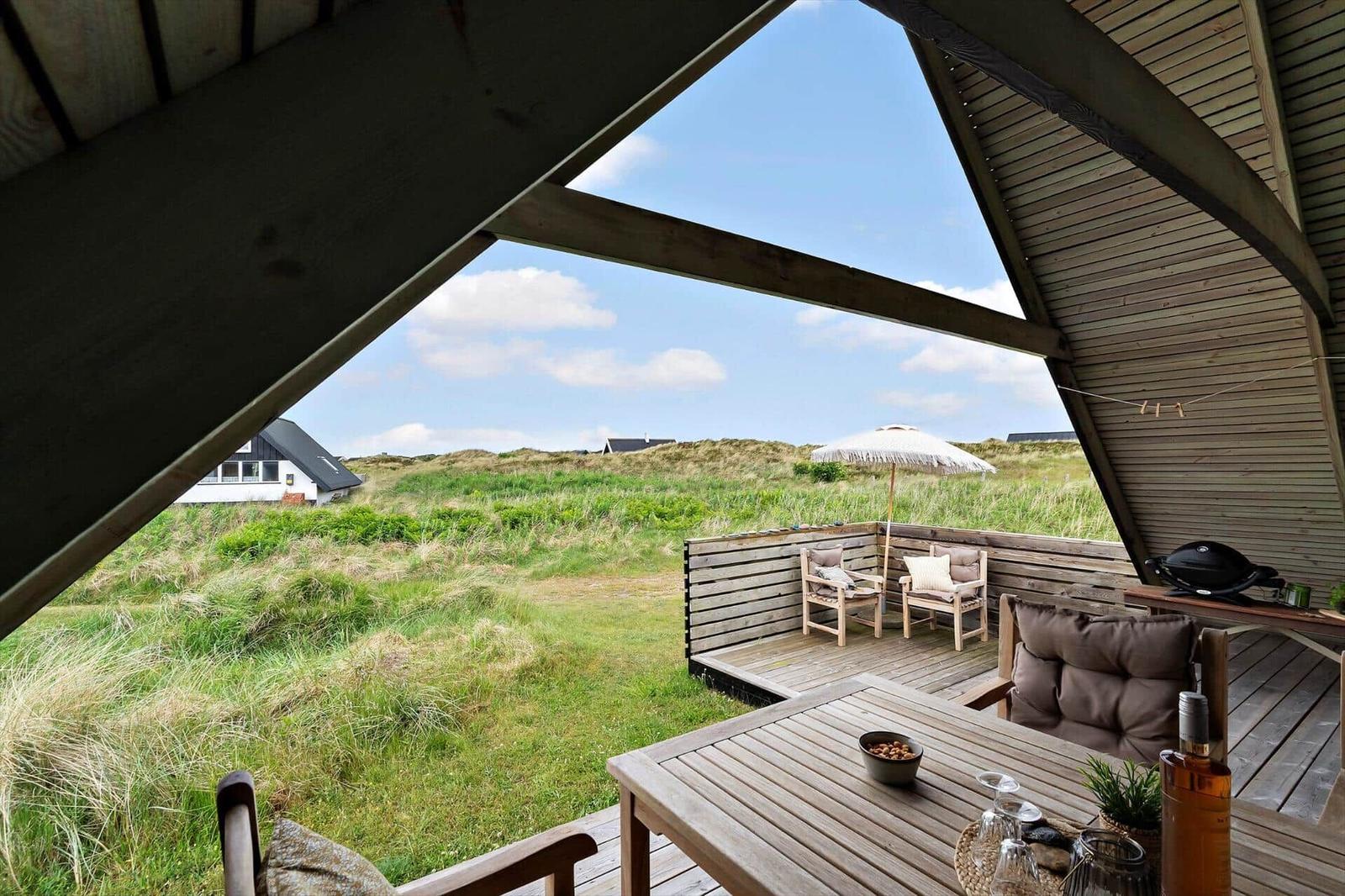 Terrasse mit Sitzgelegenheiten und Blick auf Grasland und Himmel.