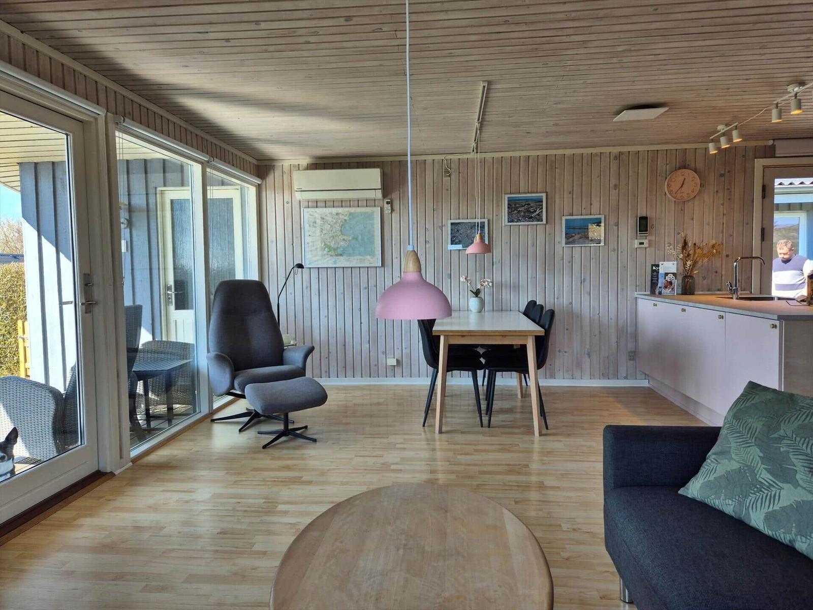 Wohn- und Essbereich mit Holzboden, Essgruppe und Sofa. Große Glasfront zur Terrasse.