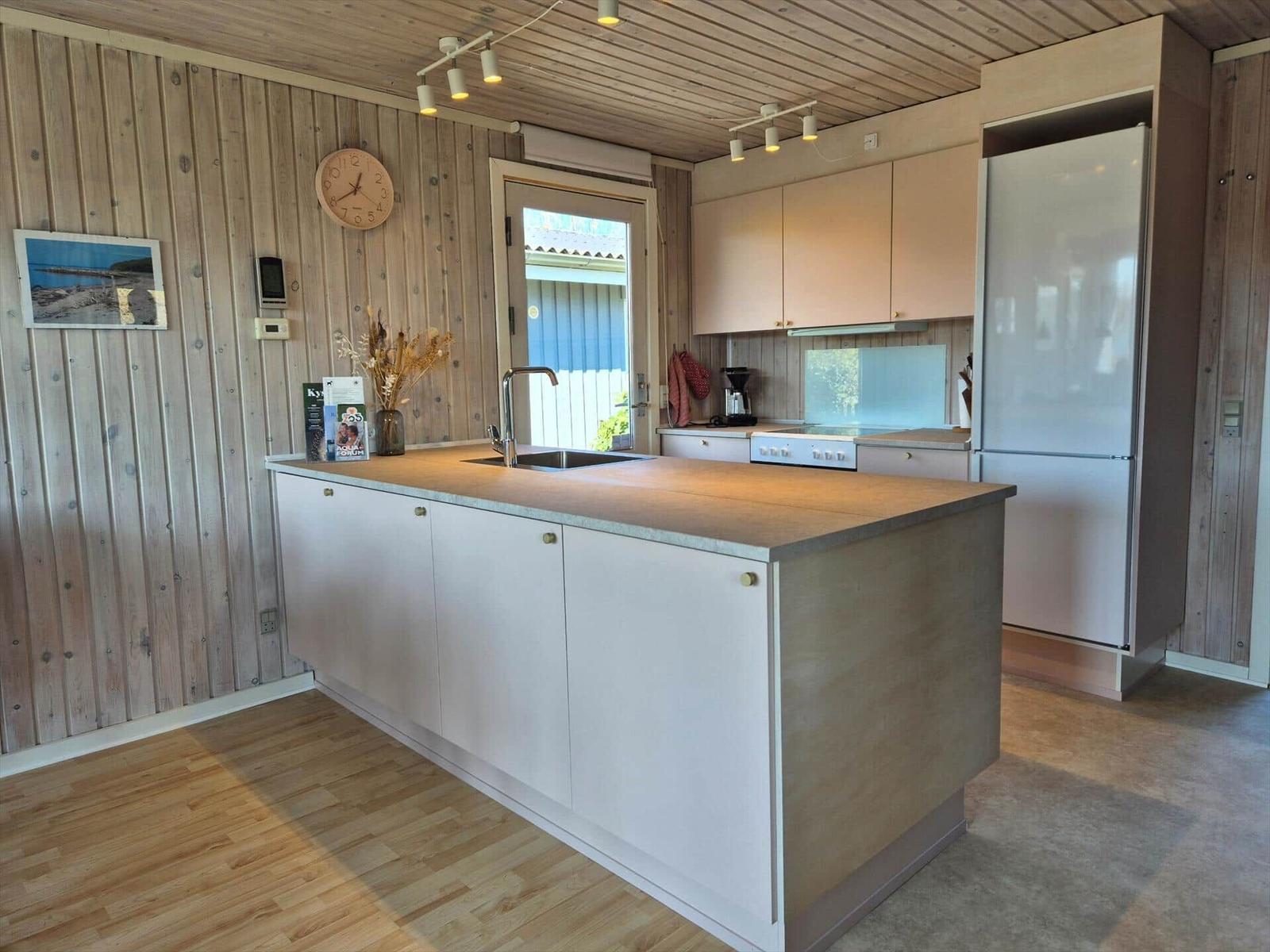 Küche mit Holzwänden, Arbeitsinsel und Kühlschrank.