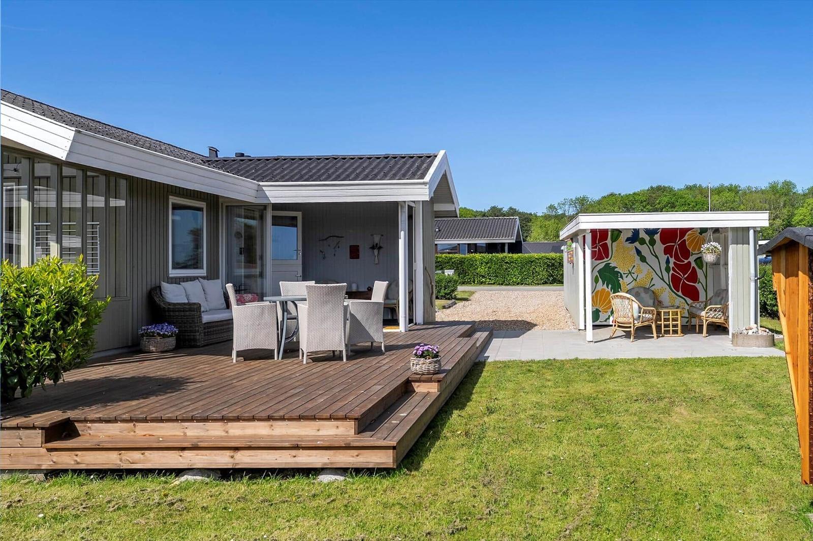 Deck with seating and garden shed with colorful wall mural.