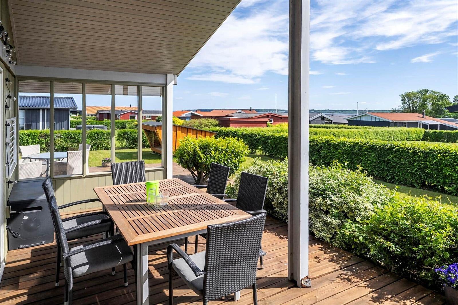 Deck with table and chairs, view of hedges and holiday homes.