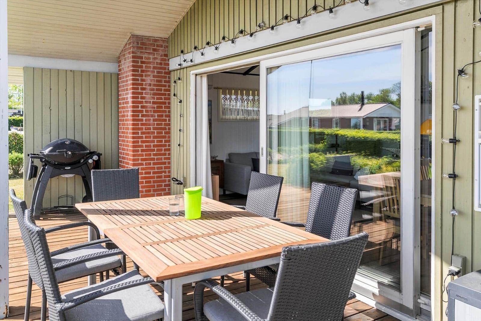 Deck with dining table, grill, and seating. Sliding glass door leads to interior.