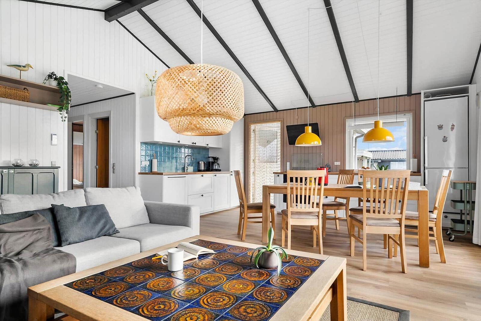 Living and dining area with kitchenette and wooden furniture under high ceiling
