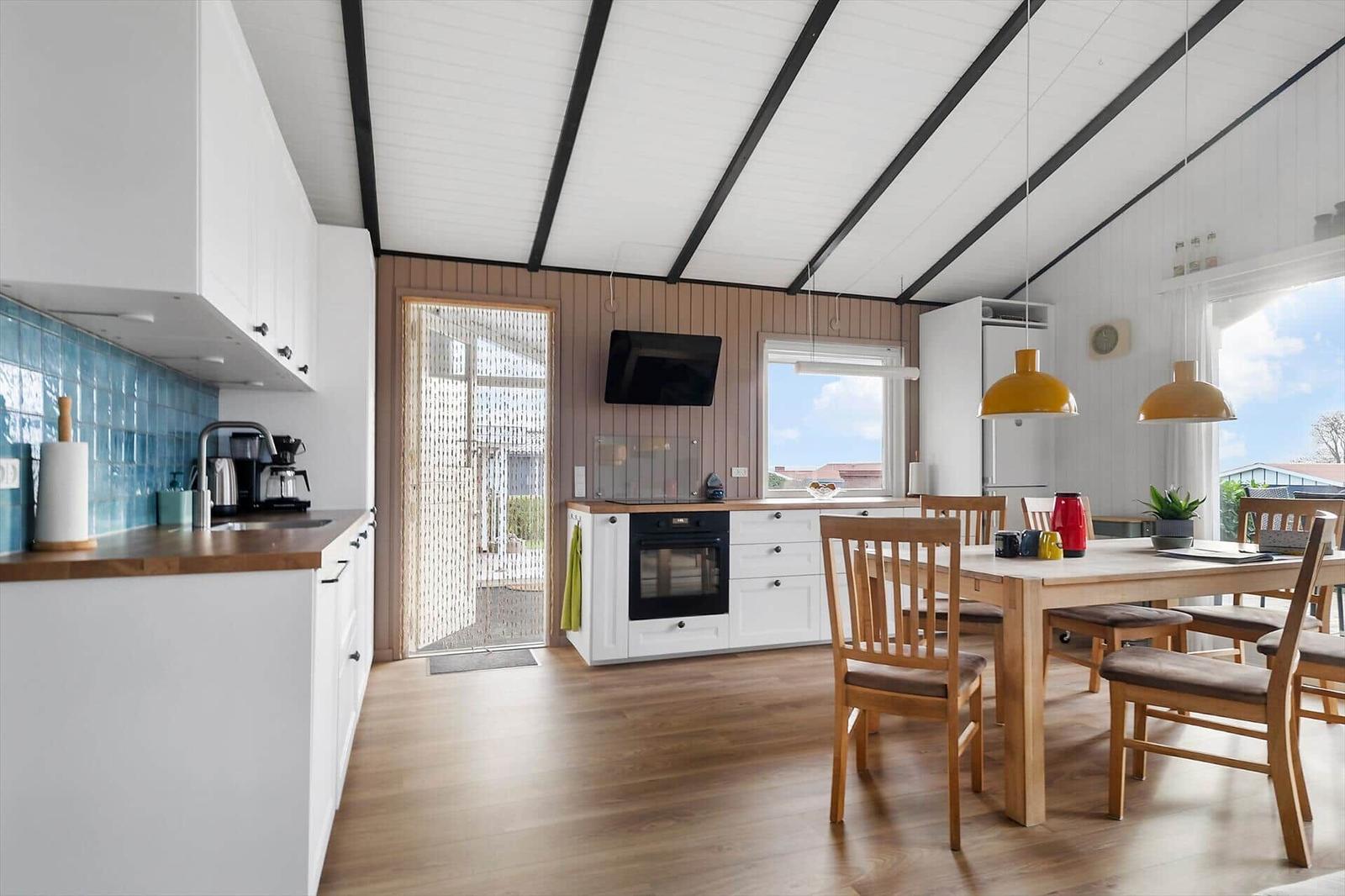 Kitchen and dining area with wooden floor, white cabinets, and blue tile backsplash.