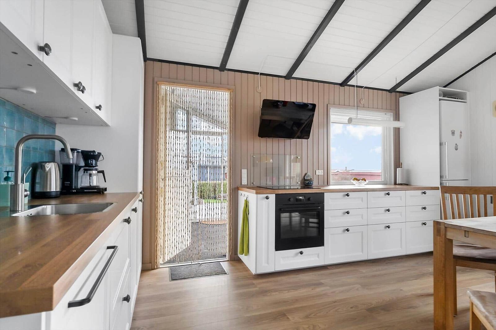 Kitchen with wooden countertops, white cabinets, and view to the outside area.