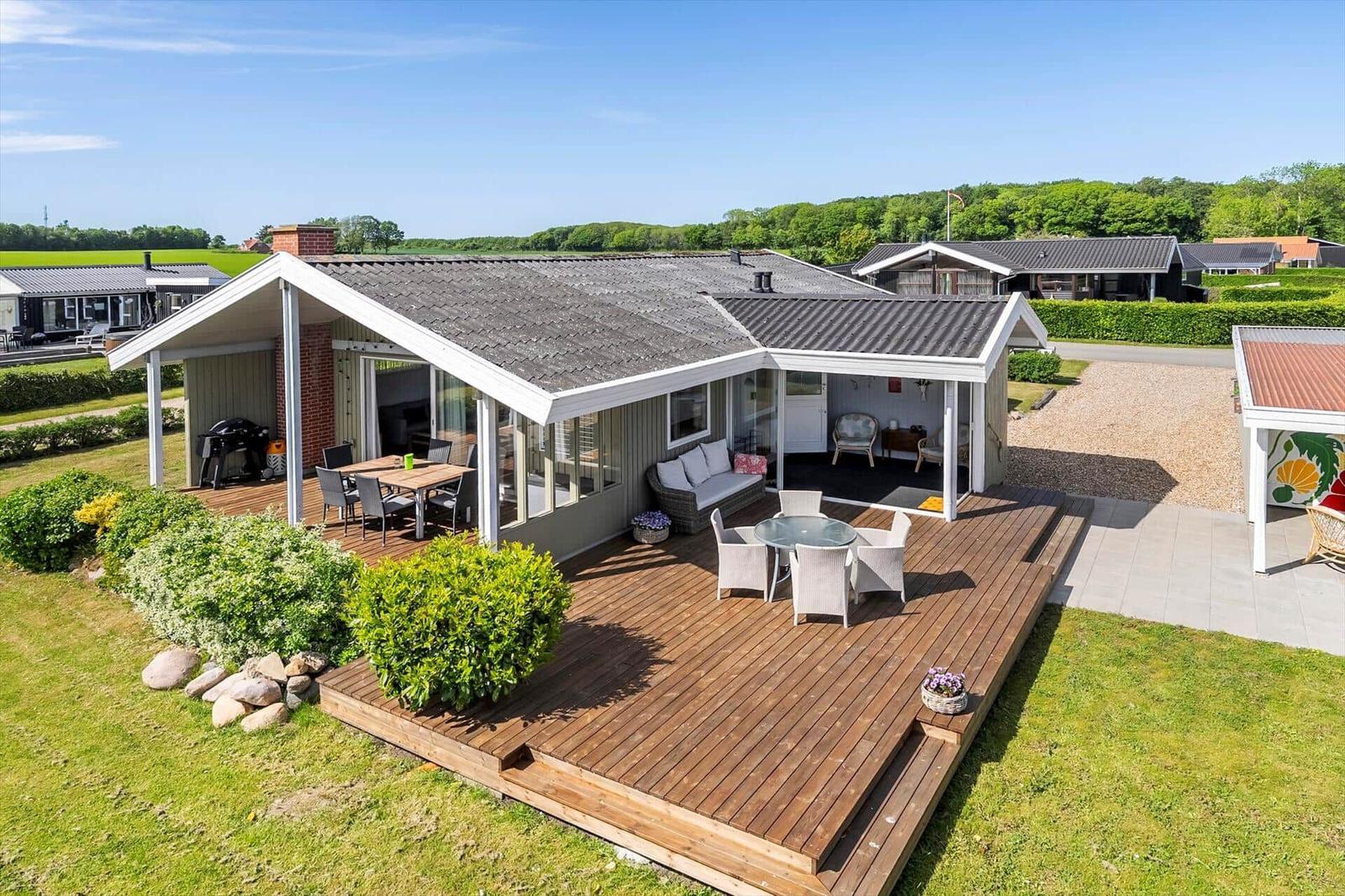 House with wooden terrace, garden, and barbecue area. View of quiet surroundings.