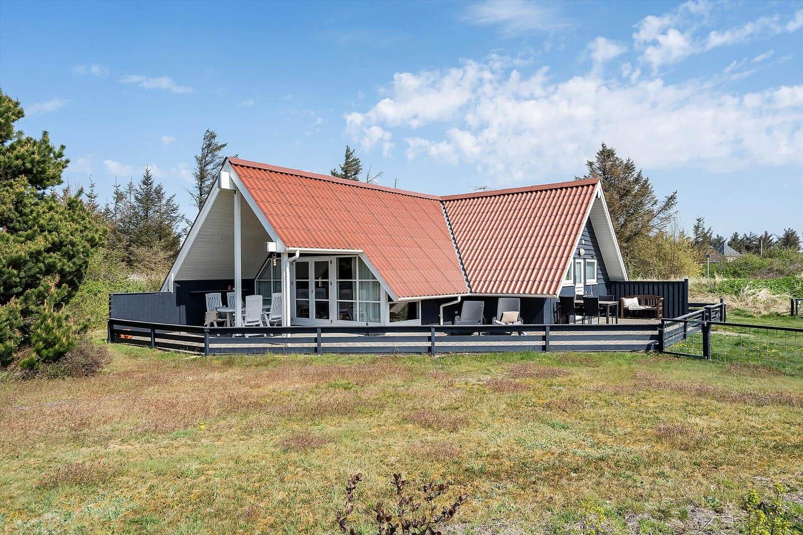 Ein Haus mit rotem Dach und Terrasse im Freien.