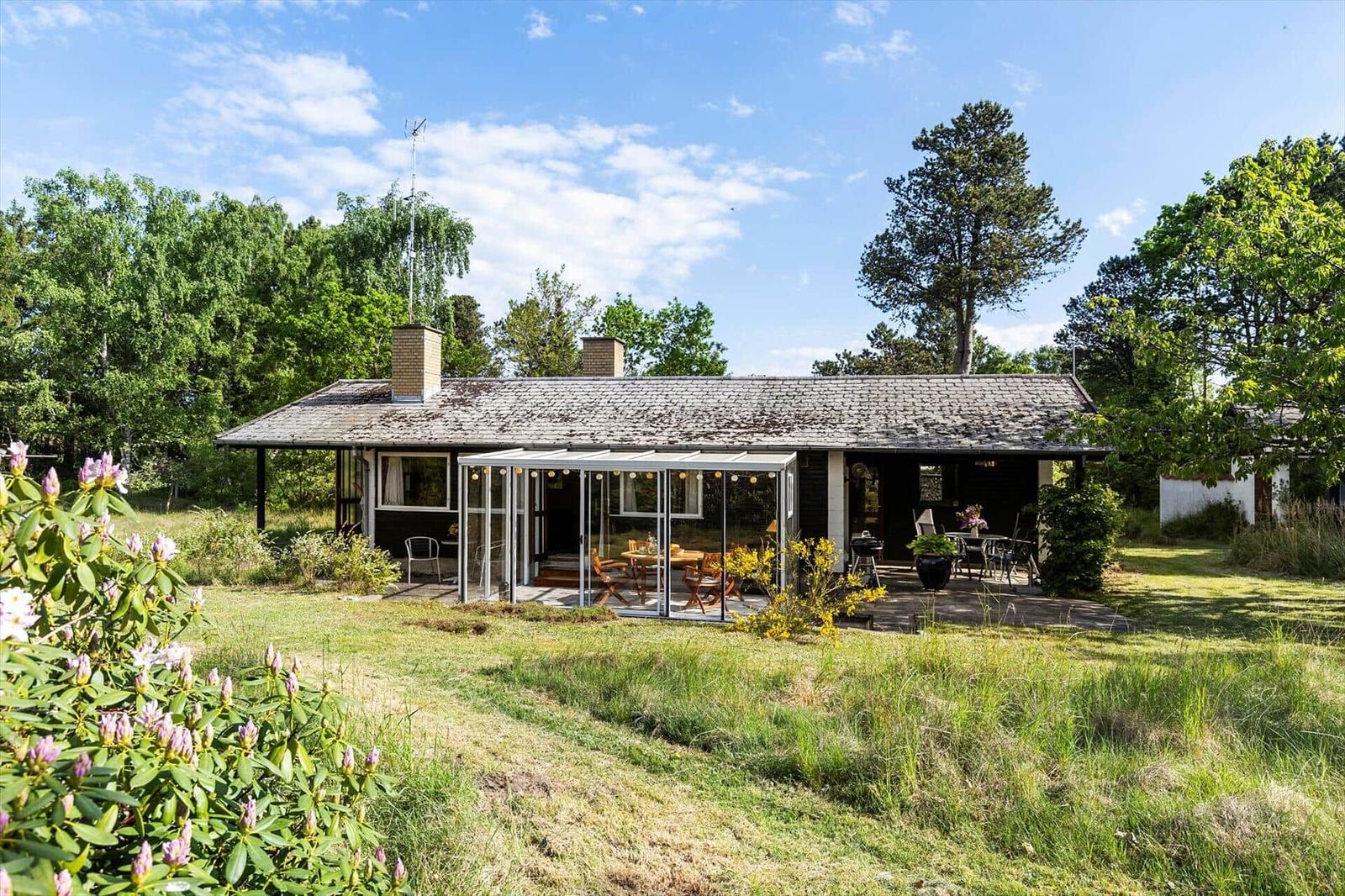 House with terrace and garden, surrounded by trees and flowers.