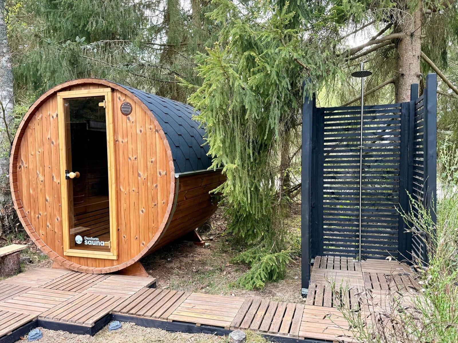 Wooden sauna with roof and shower in the forest