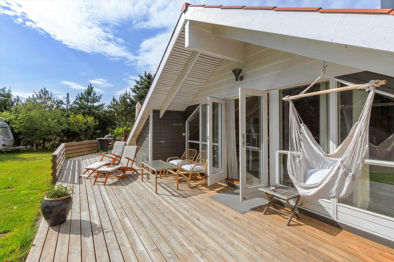 Deck with hammock, lounge chairs, and view of green lawn.