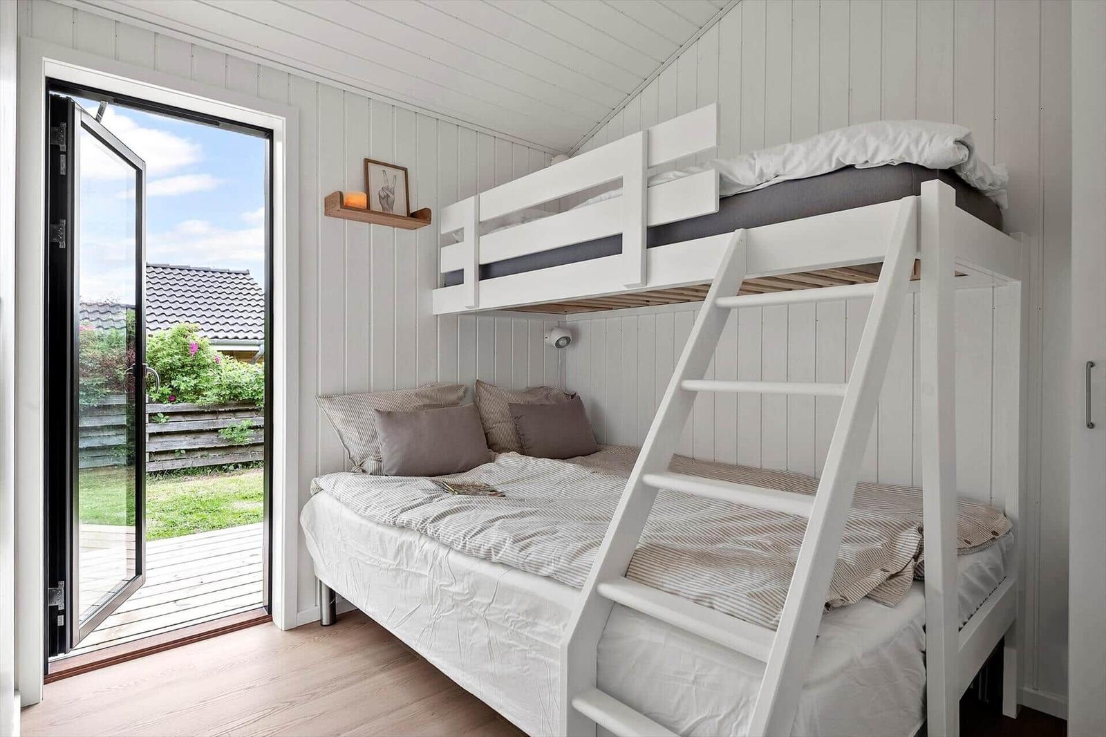 Room with bunk bed, sofa bed, and glass door to the garden.