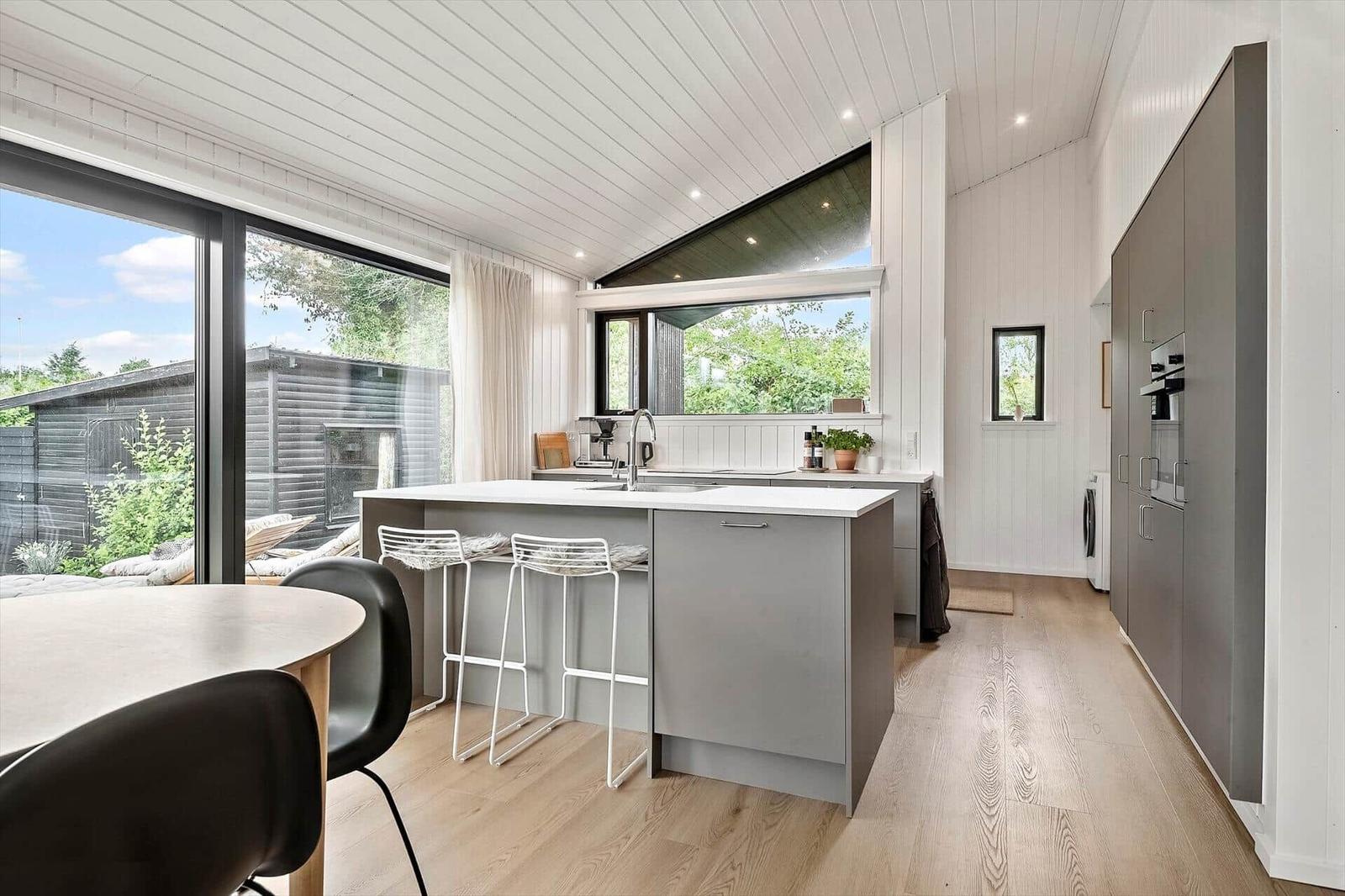 Modern kitchen with island, windows, and wooden floor.