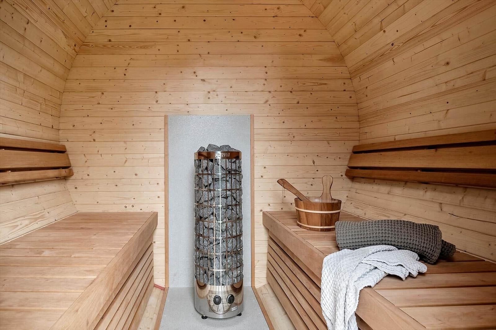 Sauna with wooden bench, stone heater, and towels.