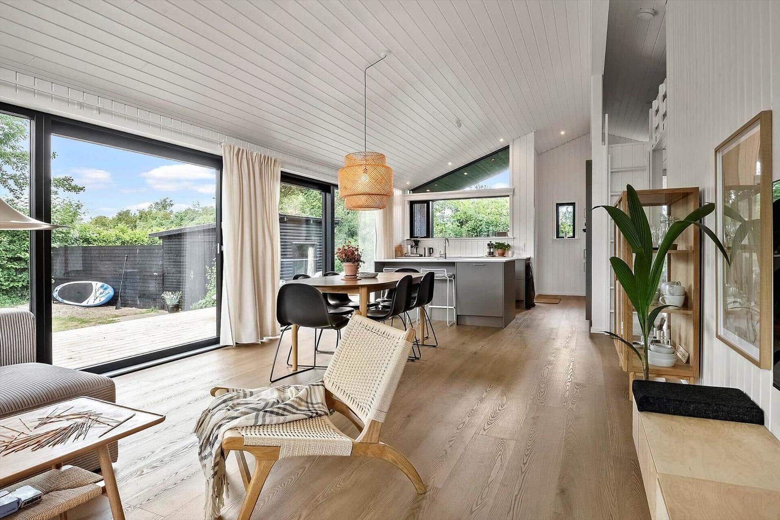 Living and dining area with wooden floor, large windows, and modern kitchen.