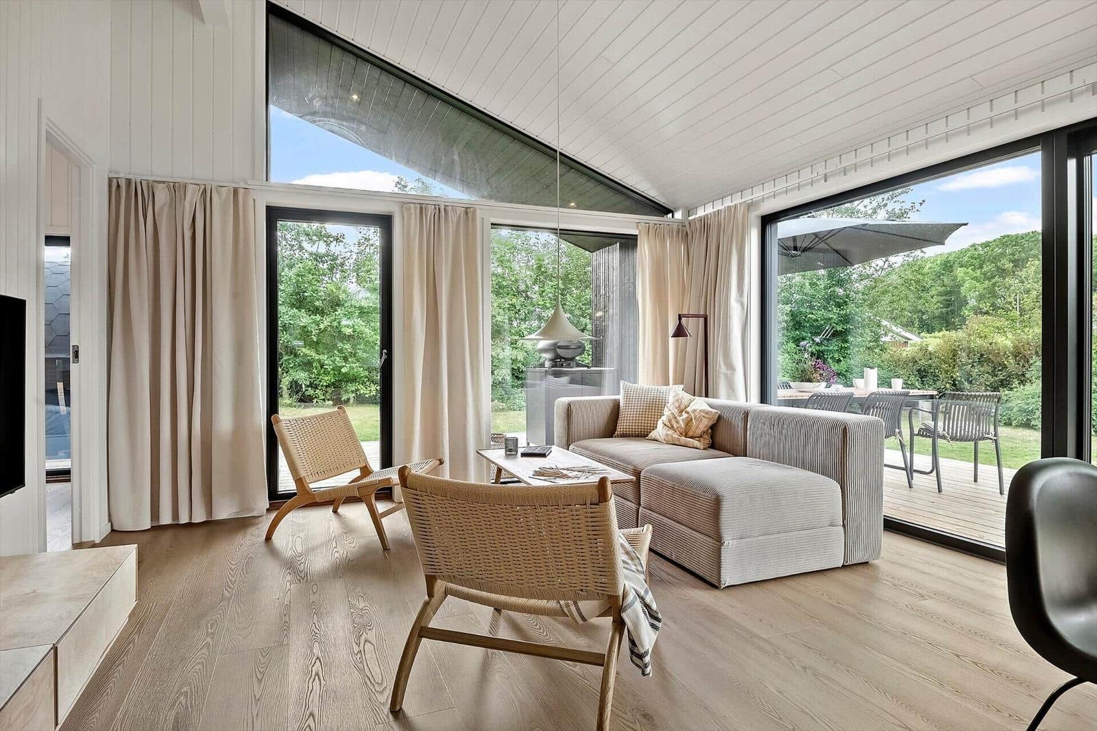 Living room with sofa, chairs, and large windows to the terrace.