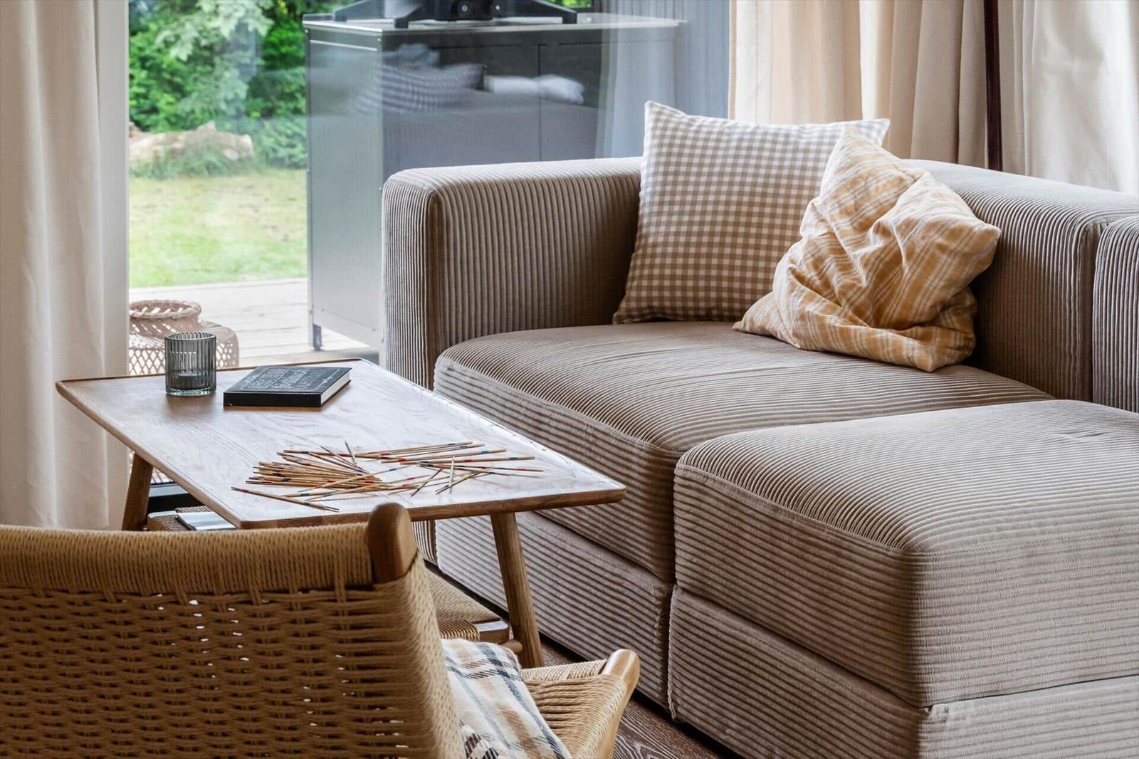 Living area with sofa, table, and chair. Garden visible outside.